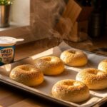 Freshly baked protein bagels on parchment with golden crust and sesame seeds