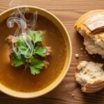 bowl of beef bone broth with steam and herbs