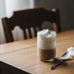 Mason jar of homemade cold foam on a wooden table