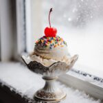 scoop of snow ice cream in vintage dish with sprinkles and cherry